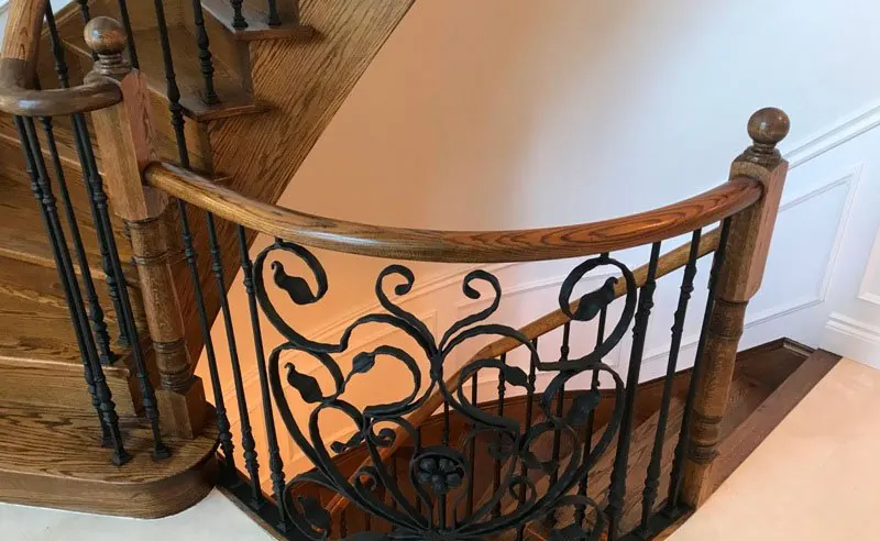 Ornate iron stair railing with oak handrail